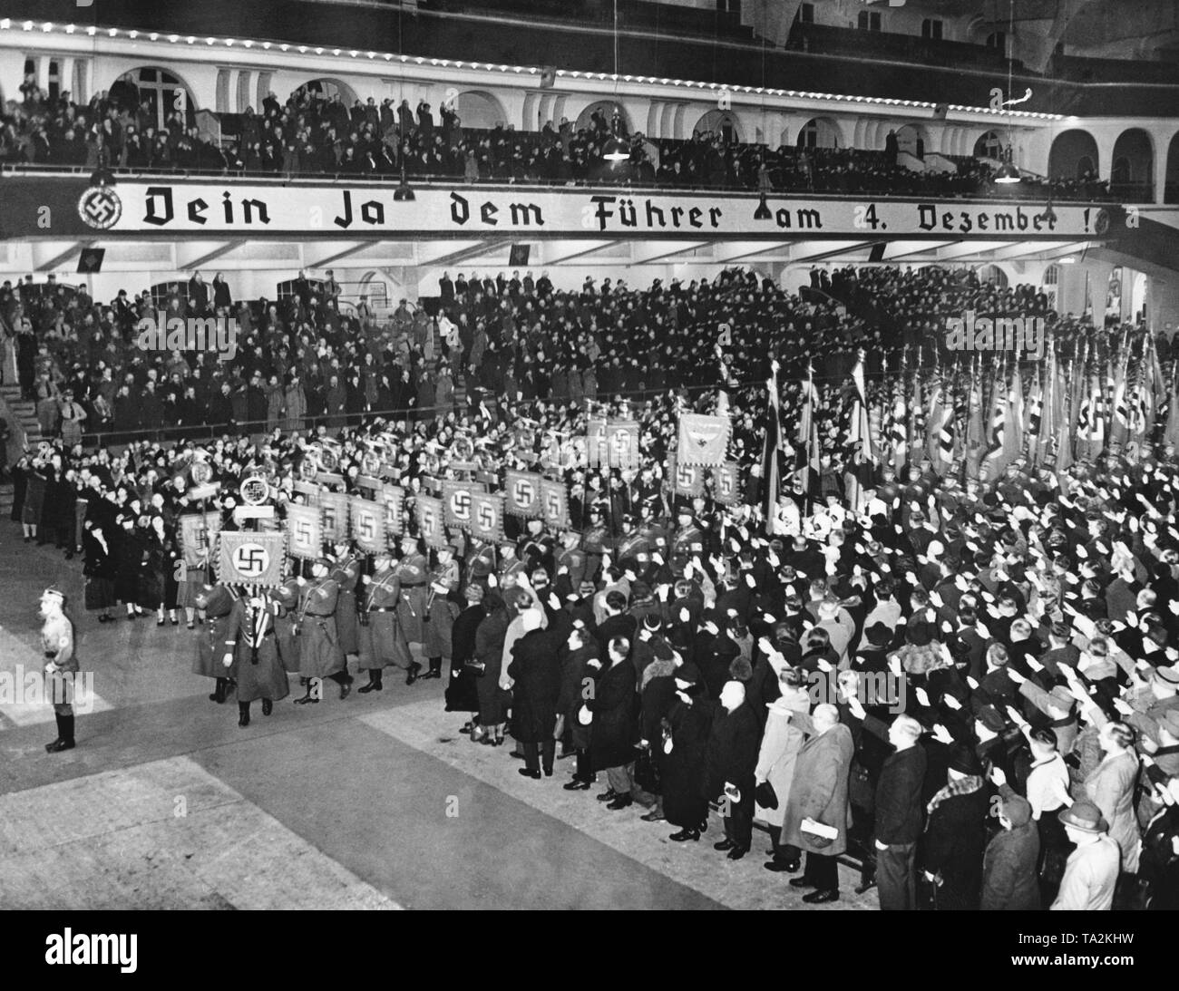 Procession of standards and flags in the Berlin Sportpalast. Election rally in Berlin on the occasion of the Sudeten German by-elections. In the plebiscite, votes are cast concerning the annexation of the Sudetenland to the German Reich. On the poster: 'Your Yes for the Fuehrer on December 4'. Stock Photo