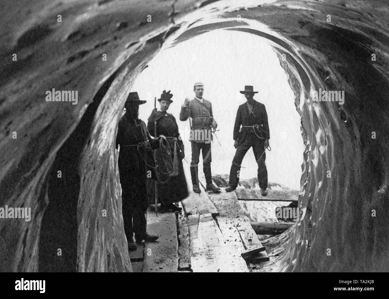 Men at the entrance of a cave in Grindelwald are knotted together through loops around their abdomen (undated picture). Stock Photo