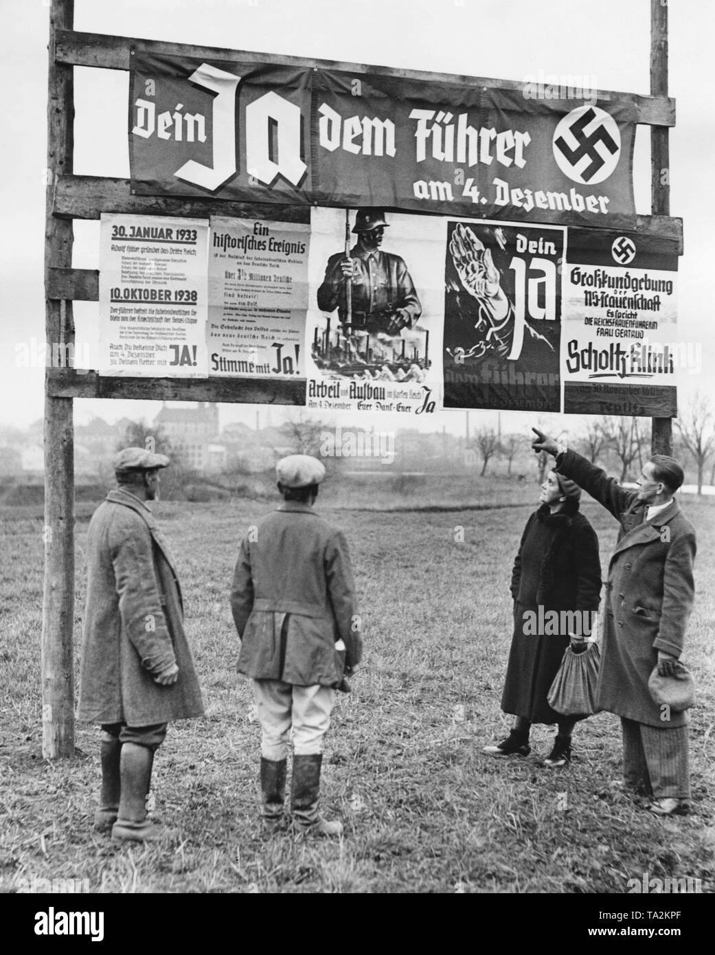 Sudeten Germans observing the election posters for the plebiscite. The Sudeten Germans cast their vote concerning the annexation of the Sudetenland to the German Reich. On the upper poster: 'Your Yes for the Fuehrer on 4 December'. Stock Photo