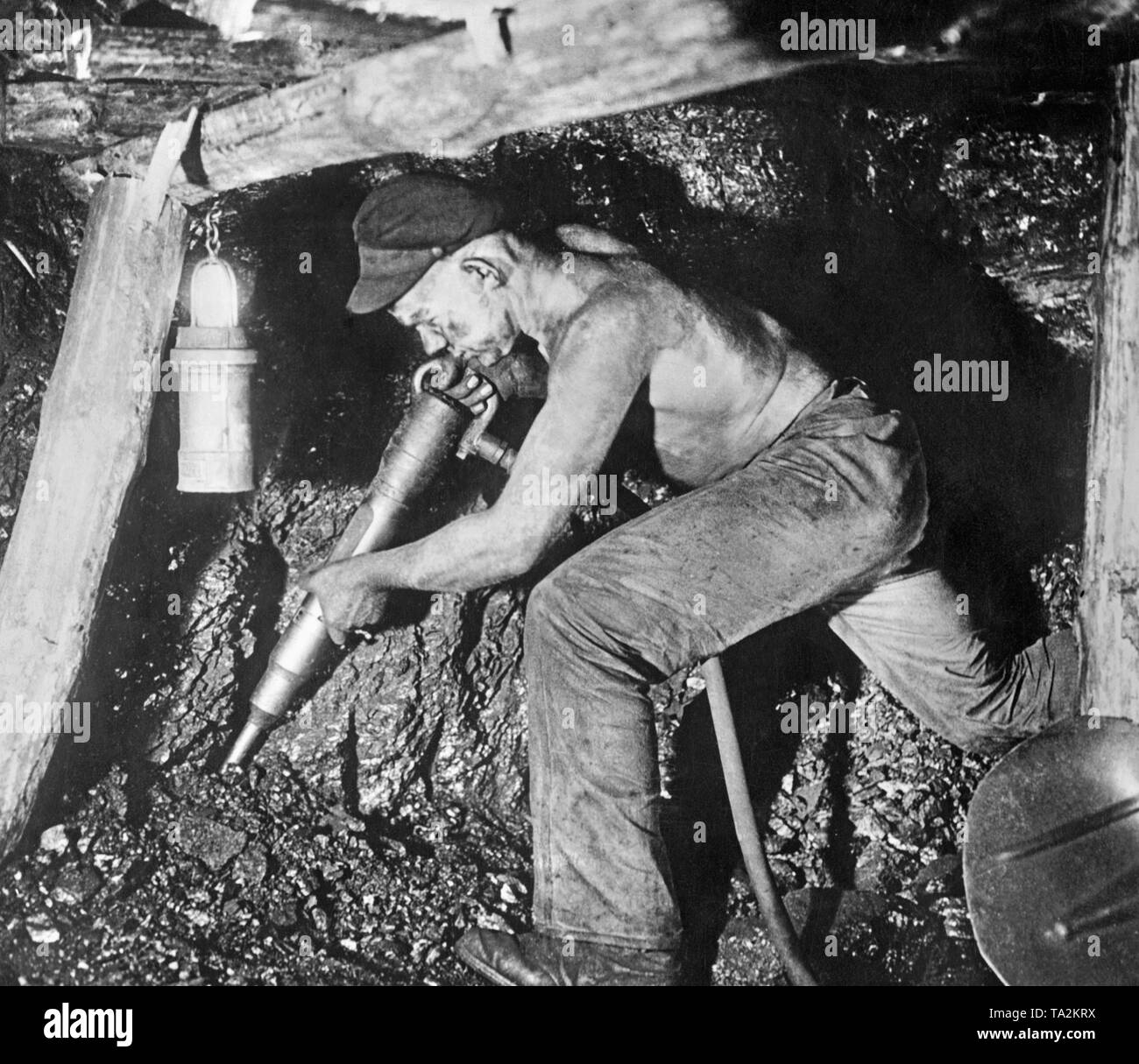 A 'faceworker' working on a coal seam with a pneumatic hammer in a West German coal mine, presumably in the Ruhr region. Stock Photo