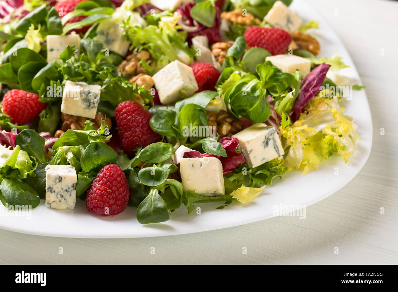 Healthy green salad with blue cheese, raspberry and walnuts Stock Photo