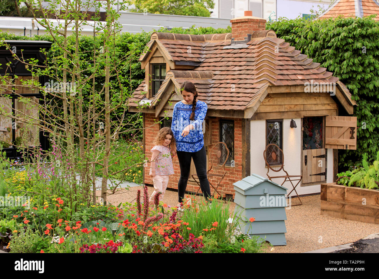 Rose Charlton age 4, from Hampshire, pictured adding the finished touches  to the garden in front of a cottage playhouse this morning at RHS Chelsea  Flower Show. Two beautiful bespoke playhouses are