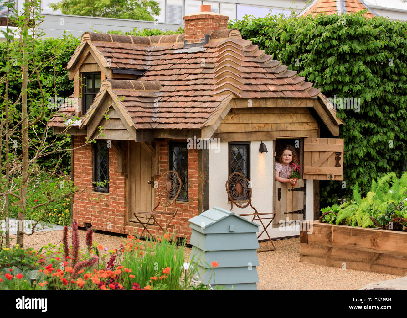 Rose Charlton age 4, from Hampshire, pictured adding the finished touches  to the garden in front of a cottage playhouse this morning at RHS Chelsea  Flower Show. Two beautiful bespoke playhouses are
