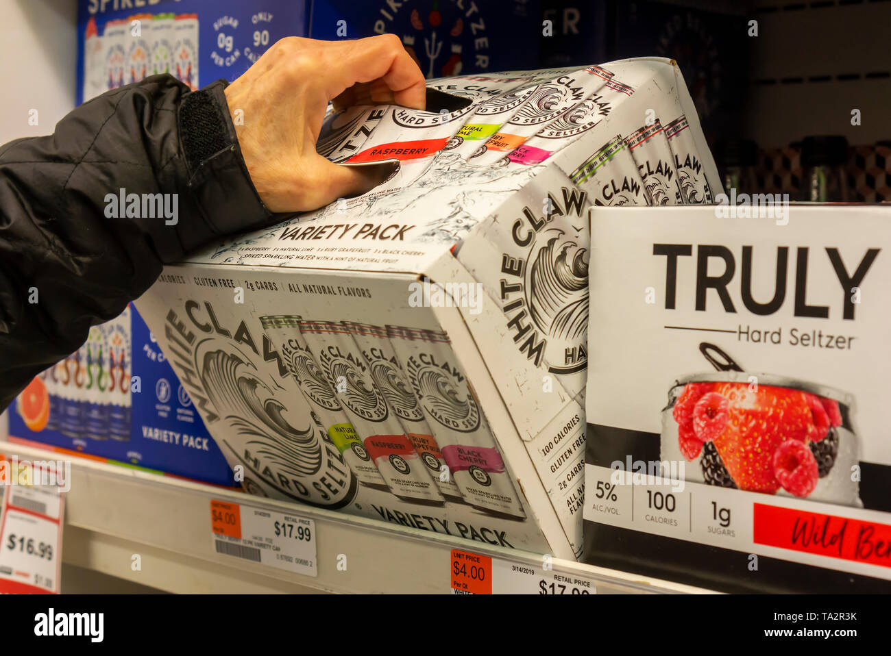 A discerning consumer chooses a case of White Claw brand hard seltzer among other brands in a cooler in a supermarket in New York on Monday, May 13, 2019. Analysts are predicting that 2019 will be the summer of hard seltzer as a number of major beer brewers get into the space as well as numerous small brewers. (Â© Richard B. Levine) Stock Photo