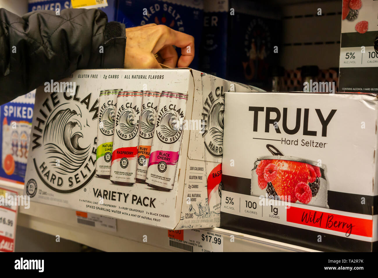 A discerning consumer chooses a case of White Claw brand hard seltzer among other brands in a cooler in a supermarket in New York on Monday, May 13, 2019. Analysts are predicting that 2019 will be the summer of hard seltzer as a number of major beer brewers get into the space as well as numerous small brewers. (Â© Richard B. Levine) Stock Photo