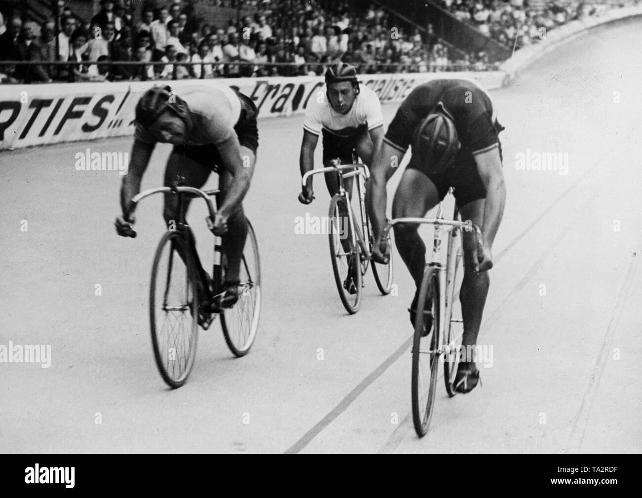 Three track cyclists during a sprint ride on the racing track at the Parc des Princes. Stock Photo