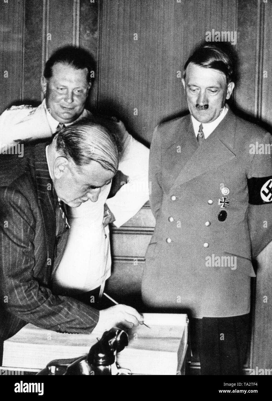French Prime Minister Edouard Daladier signs the guestbook during the Munich conference on the Sudeten crisis, in the presence of Hermann Goering (left) and Adolf Hitler (right), Stock Photo