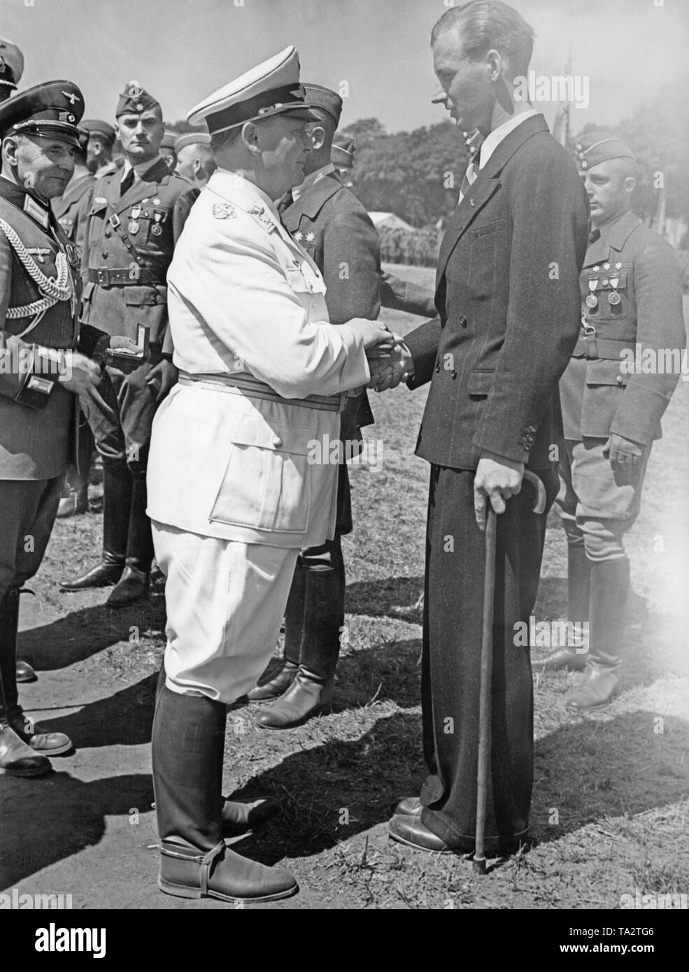 Photo of Field Marshal Marshal Hermann Goering (in white uniform) while awarding a wounded pilot oficer at a parade on the military training ground in Doeberitz near Berlin on the 5th of June, 1939. Stock Photo