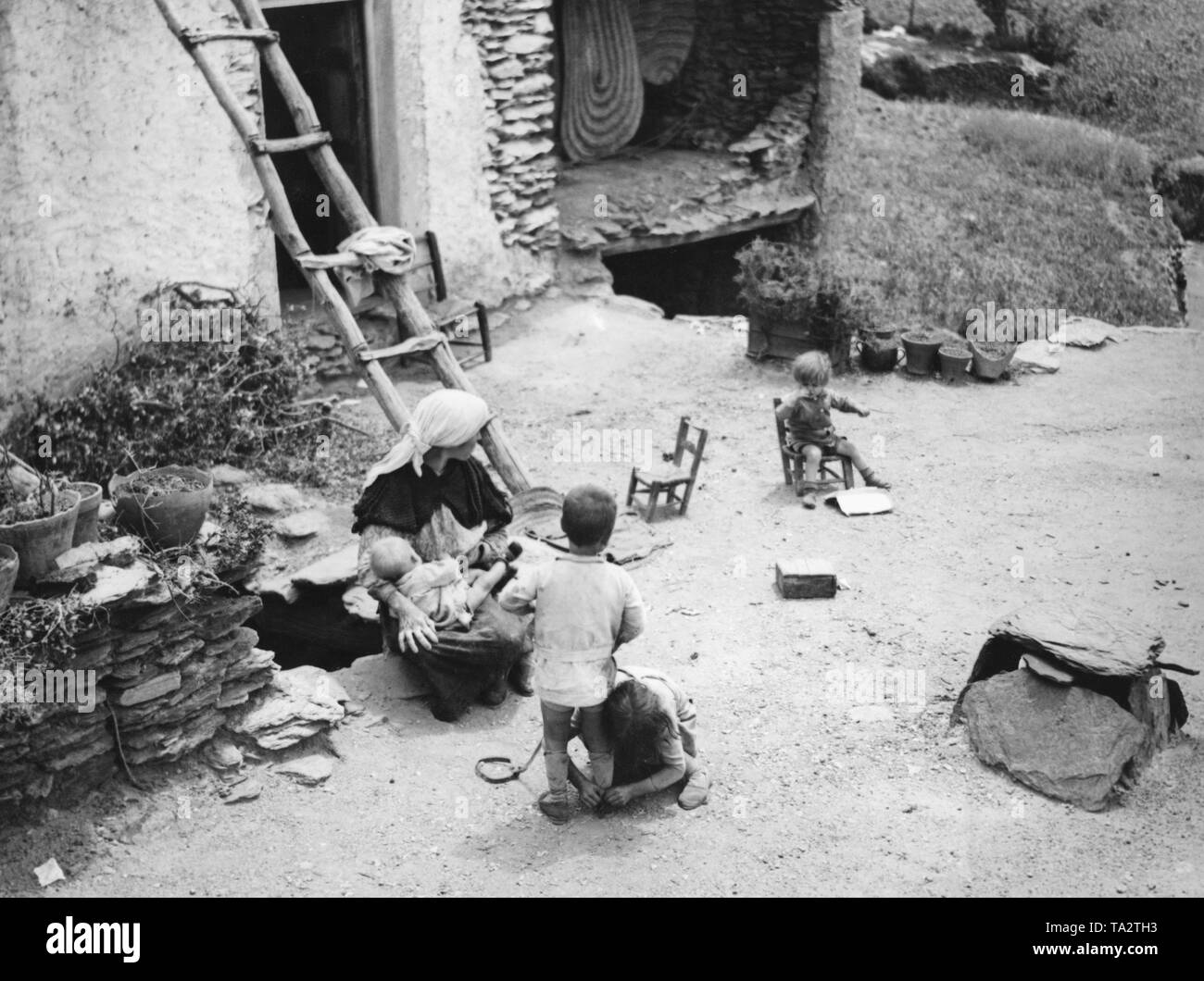 Spanish woman with her children on the flat roof of her house. Right in front the air shaft of the house below. Stock Photo