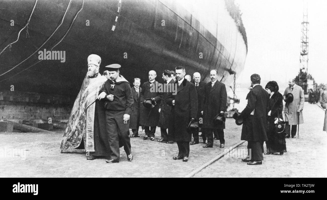 Shortly before the outbreak of the First World War, the Russian Tzar issued an order to the shipyard in Gdansk for the construction of small cruisers for the Russian fleet. This photograph shows the Russian Provost von Maltzew, who, supported by a German sailor, visits the Schichau-Werke shipyard in Gdansk. They also inspect the new cruiser before the consecration. Stock Photo