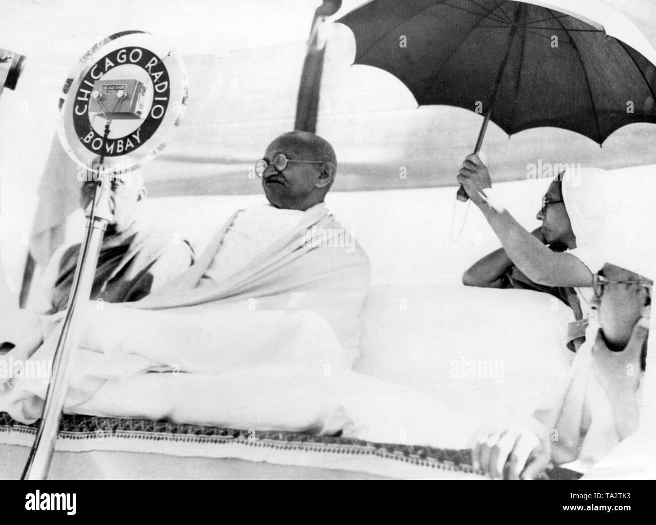Mahatma Gandhi opens the All India Swadesi exhibition in Vithalnagar, Huripura. There takes place the 51st Indian National Congress. Behind him sits his secretary Madeleine Slade, Mirabehn, holding a sunshade over his head. Stock Photo