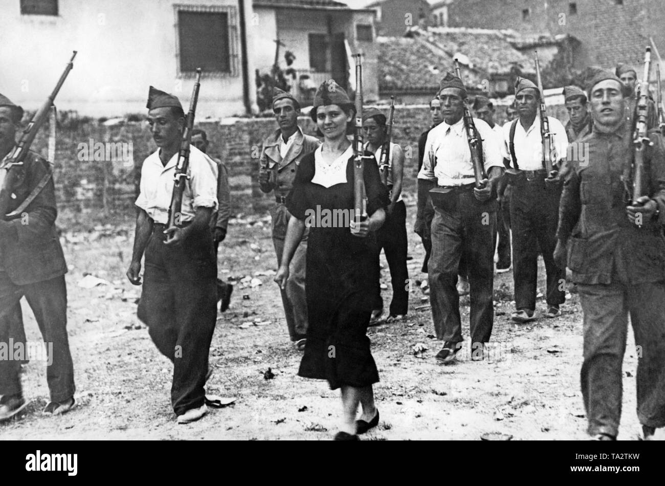 Photo of a unit of volunteer Republican militiamen with shouldered carabiners during the Spanish Civil War in 1936. In the center, a female fighter in a dress with the typical military Gorillo cap. The soldiers wear alpargatas, light cotton shoes with braided hemp soles. Stock Photo
