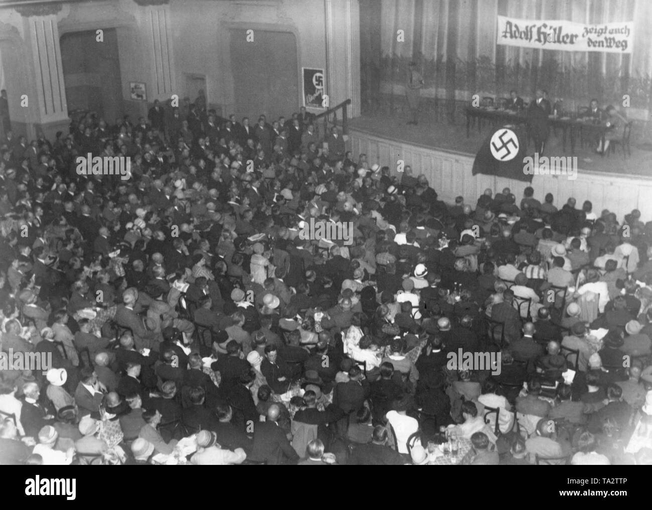 A speech is held in front of an audience at a meeting of the NSDAP in the Berlin Hasenheide. The banner reads: 'Adolf Hitler shows you the way'. Stock Photo