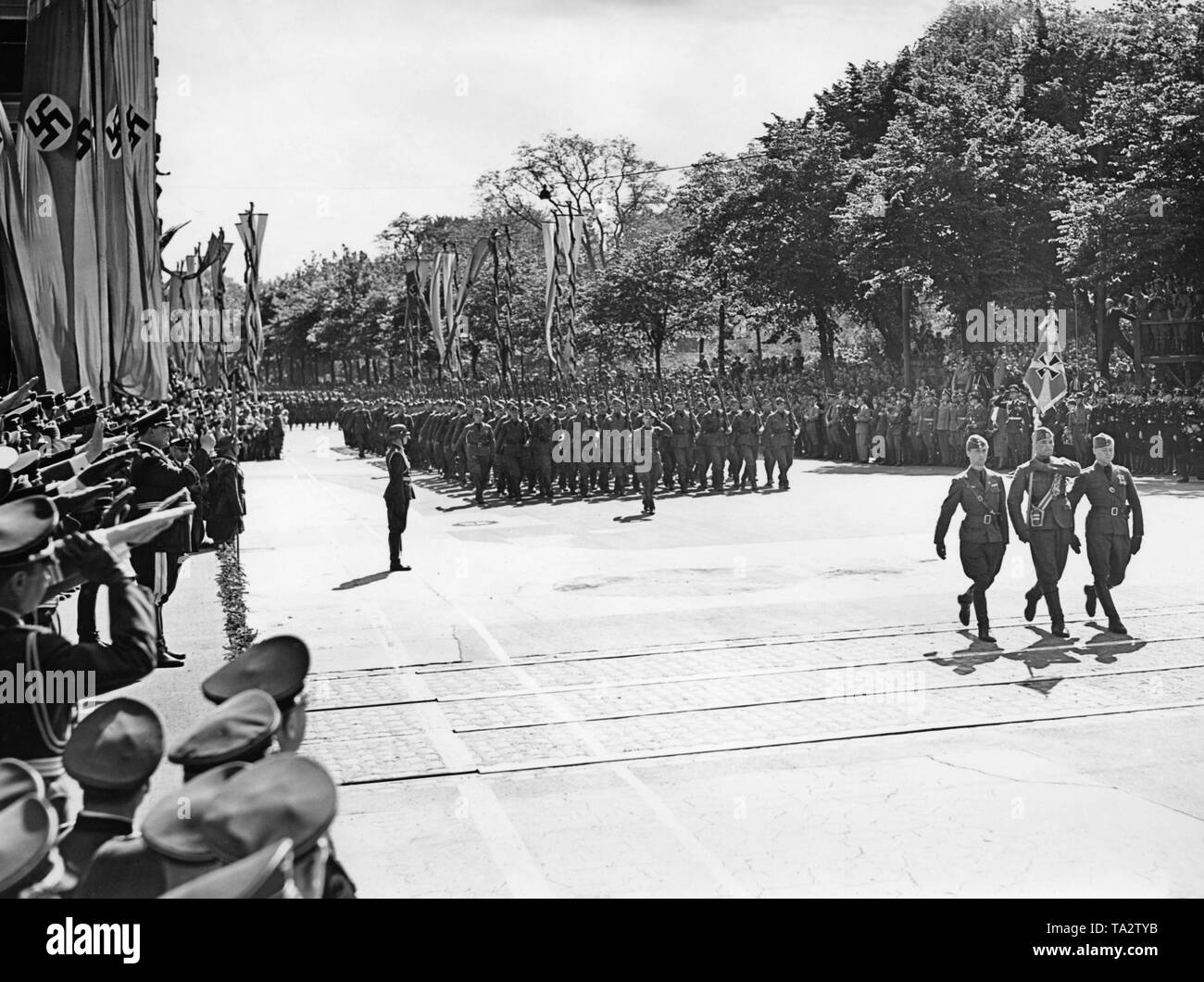 Photo of a unit of the Condor Legion marching in front of Field Marshal General Hermann Goering (on the right with general's baton, chief commander of the Luftwaffe) at Karl Muck Platz (today Johannes Brahms Platz) in Neustadt, Hamburg. In the front, color guards, two officers and a corporal with the regimental standard are parading. Stock Photo