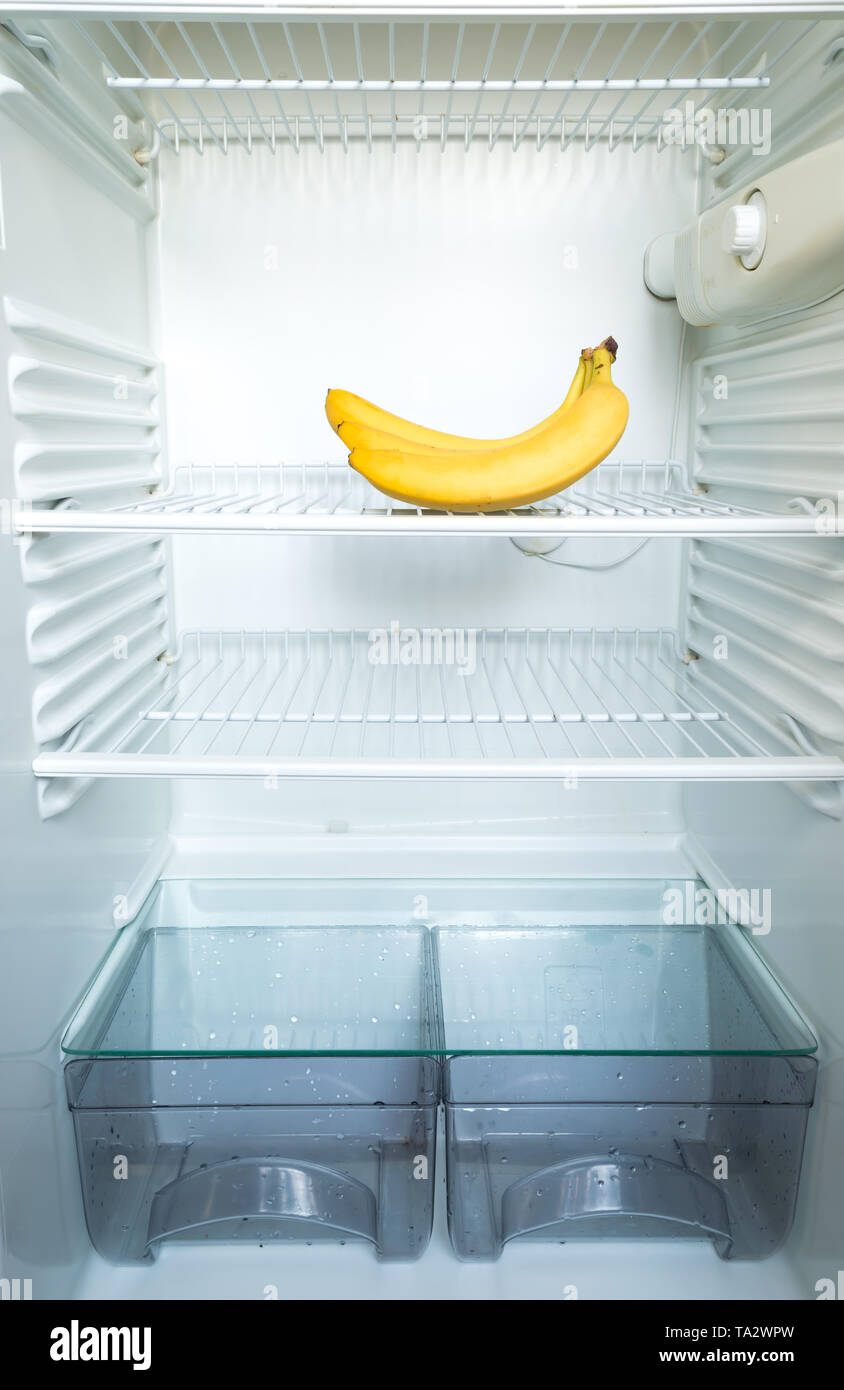 Bright fresh bananas on shelf of open empty refrigerator. Weight loss