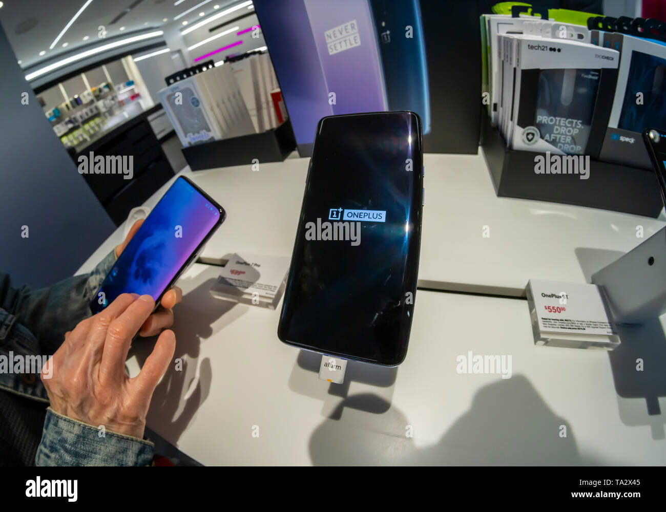 A visitor to a T-Mobile store in New York tries out the OnePlus 7 Pro smartphone on Thursday, May 16, 2019. The smartphone brand has a following which admires the smartphones for their features but with a lower price point than the iPhone or Samsung flagship devices.  (© Richard B. Levine) Stock Photo