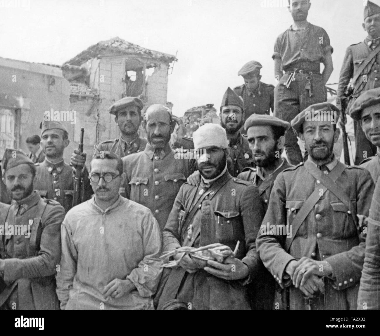 Photo of a group of soldiers of the Guardia Civil, after the seven-week siege of the Alcazar of Toledo after its liberation on September 26, 1936. In the center, a wounded man holds a plucked chicken. Stock Photo