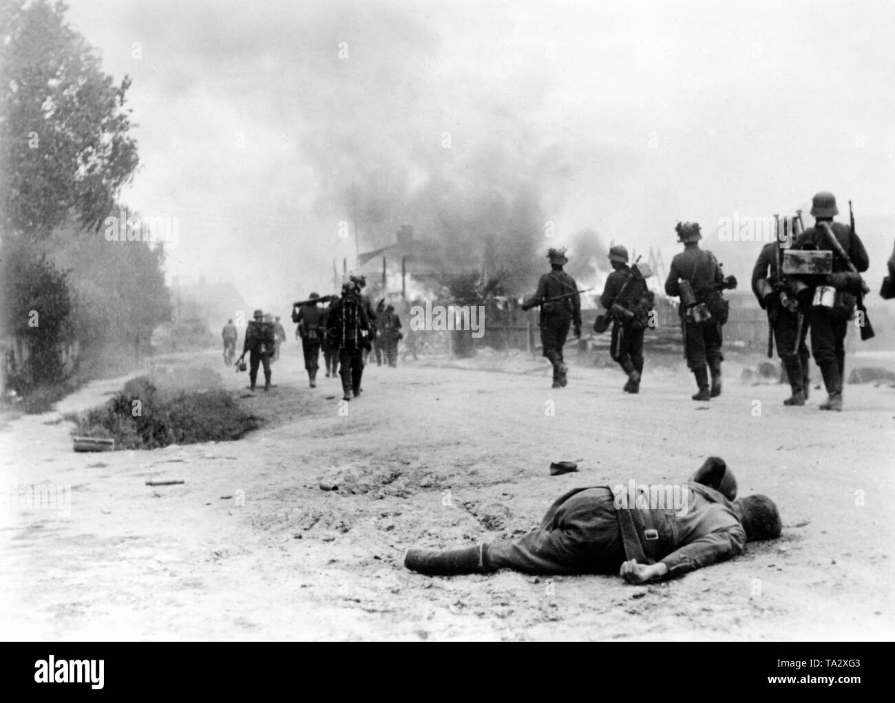 German infantry on one of the advance road to the east. The soldiers in the left center carries a disassembled grenade launcher Granatwerfer 34th In the foreground a fallen Red Army soldier. Stock Photo