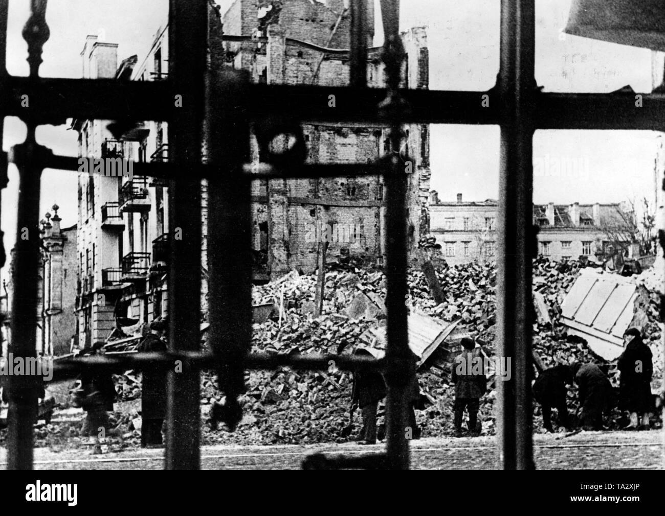 View of debris through bars in downtown Orel (Orjol). Civilians search in the rubble for usable pieces. Presumably, this photo was taken shortly before the reconquest of the city by Soviet troops in late July or in early August, 1943. Stock Photo