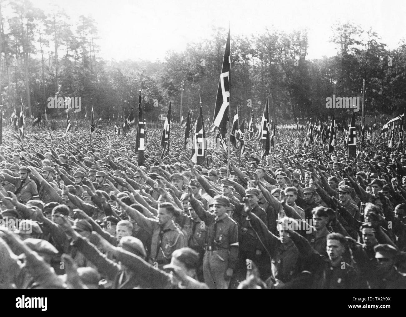 Members of the Hitlerjugend march in the Potsdamer Stadion on the Reichsjugendtag (Reich Youth Day) and show the Nazi salute, while Adolf Hitler speaks to them. Stock Photo