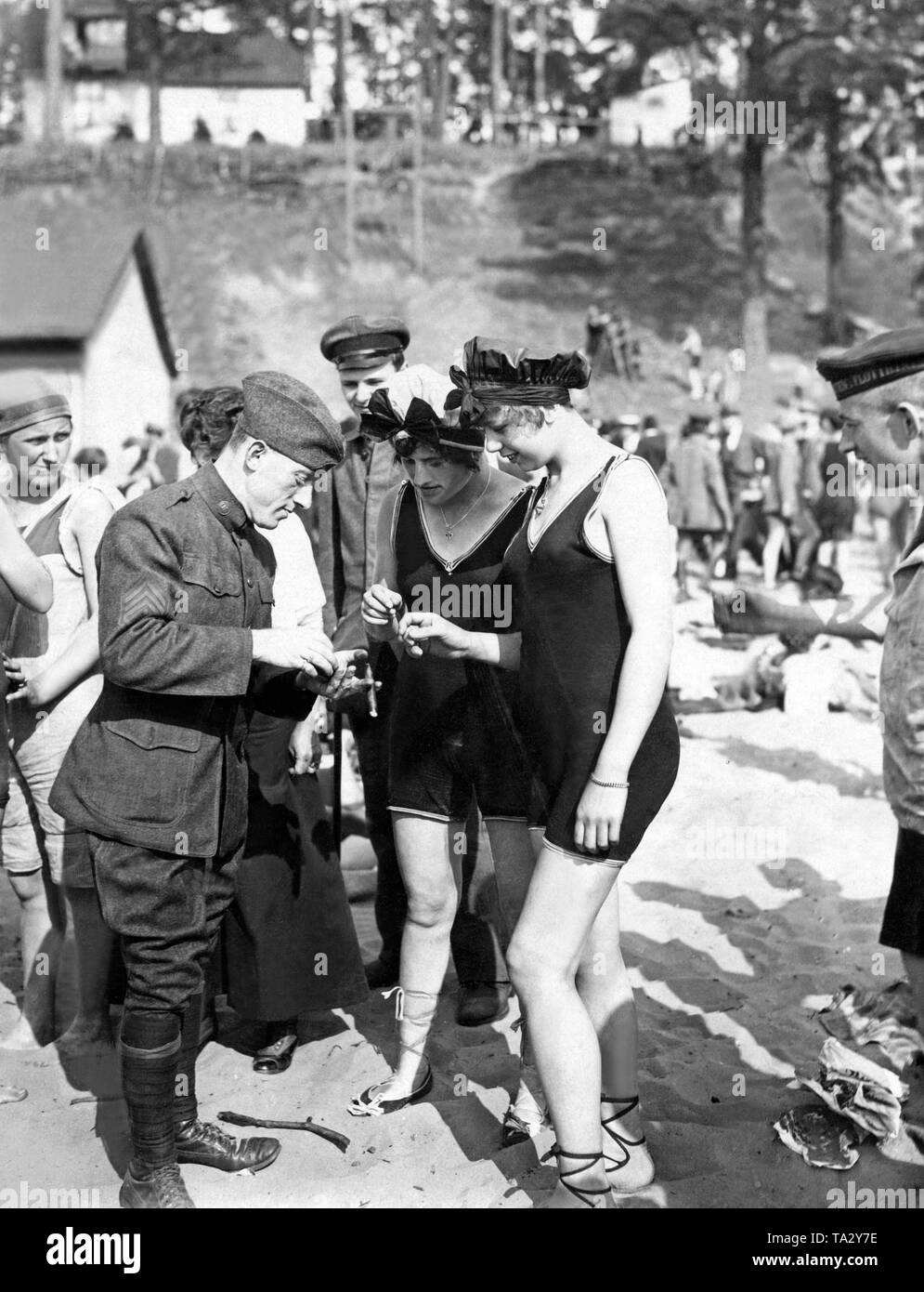 Two women in bathing costumes talk with an American soldier in uniform in the Wannsee open-air pool. Stock Photo