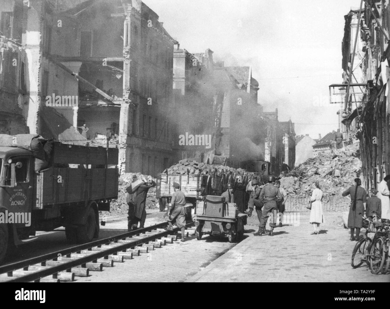 A rubble transporting train in the Georgenstrasse in Munich. German prisoners, guarded by American soldiers, are clearing the rubble. Stock Photo