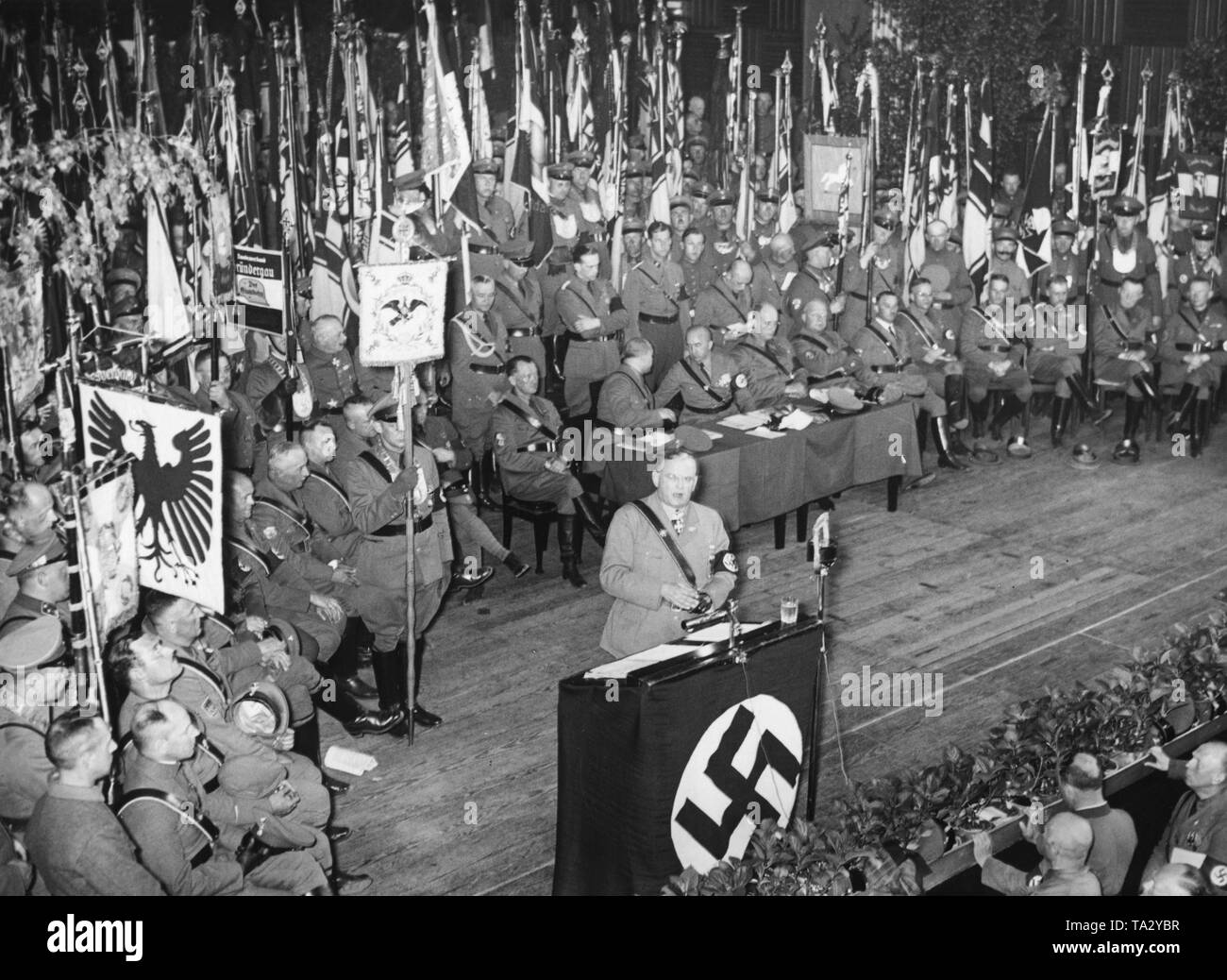 Bundesfuehrer (federal leader) Franz von Seldte is holding a speech at the Reich leadership meeting of the Alliance of Red Front-Fighters (Stahlhelm) in the city hall of Magdeburg. Behind him, flags, standards, and at the table (in the middle from left) co-founder and lawyer Rudolf Schaper, Federal Chancellor Theodor Gruss, Chancellor Johannes Bock, Bundespressechef Wilhelm Kleinau and co-founder and lawyer Gustav Buenger. Stock Photo