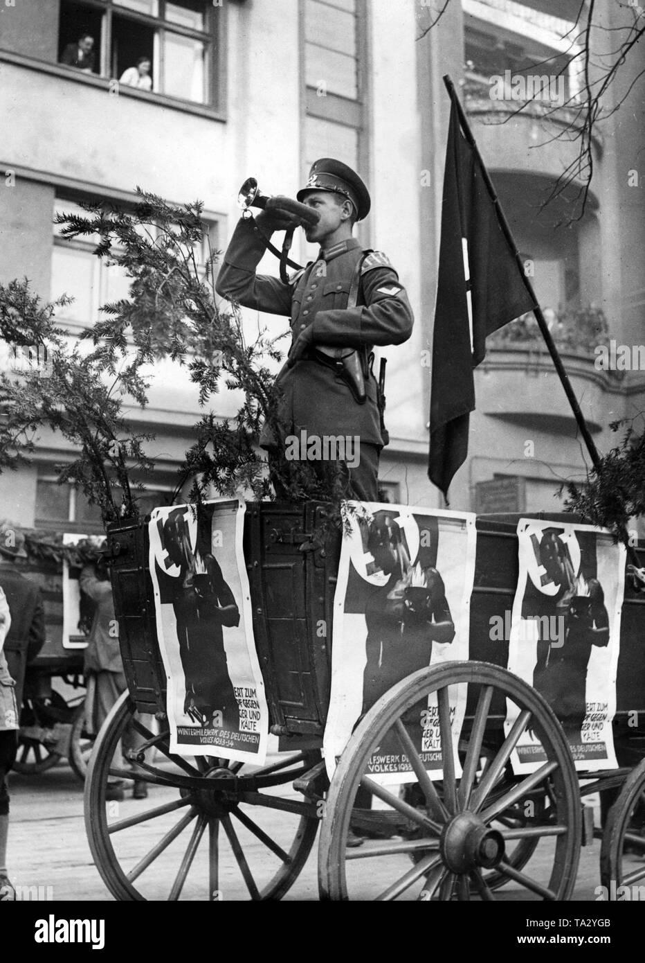 A Reichswehr trumpeter on a cart of the Winterhilfswerk with posters for the collection of clothes. Stock Photo