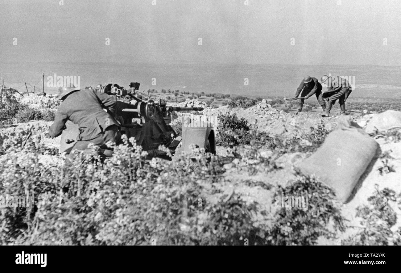 Photo of two gunners of the German Condor Legion, that are demolishing a wall at Toledo, during one of the last battles of the Spanish Civil War. Their purpose is to aim unhindered with the 2cm FLAK 30 at the enemy positions in the background. Stock Photo