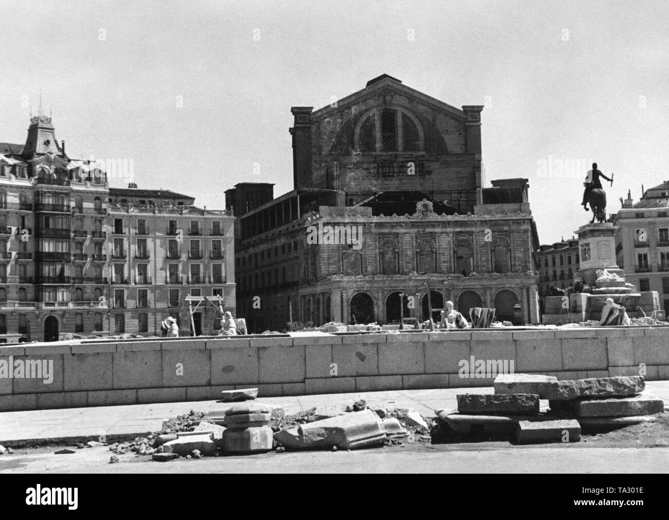 Photo of the Plaza del Oriente in Madrid after the invasion of the Spanish troops under General Francisco Franco in the spring of 1939. In the background, the partially destroyed Teatro Real opposite the Spanish Royal Palace (Palacio Real). The pavement of the square is torn open for barricade construction. Children are playing. Stock Photo