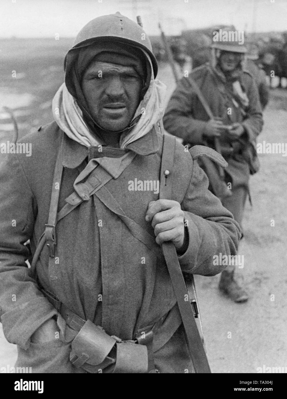 Photo of two completely exhausted Italian soldiers of the Corpo Truppe Volontarie at the front during the Battle of Guadalajara in March, 1937.  The soldiers wear caps and scarves under their uniform against the cold. Stock Photo