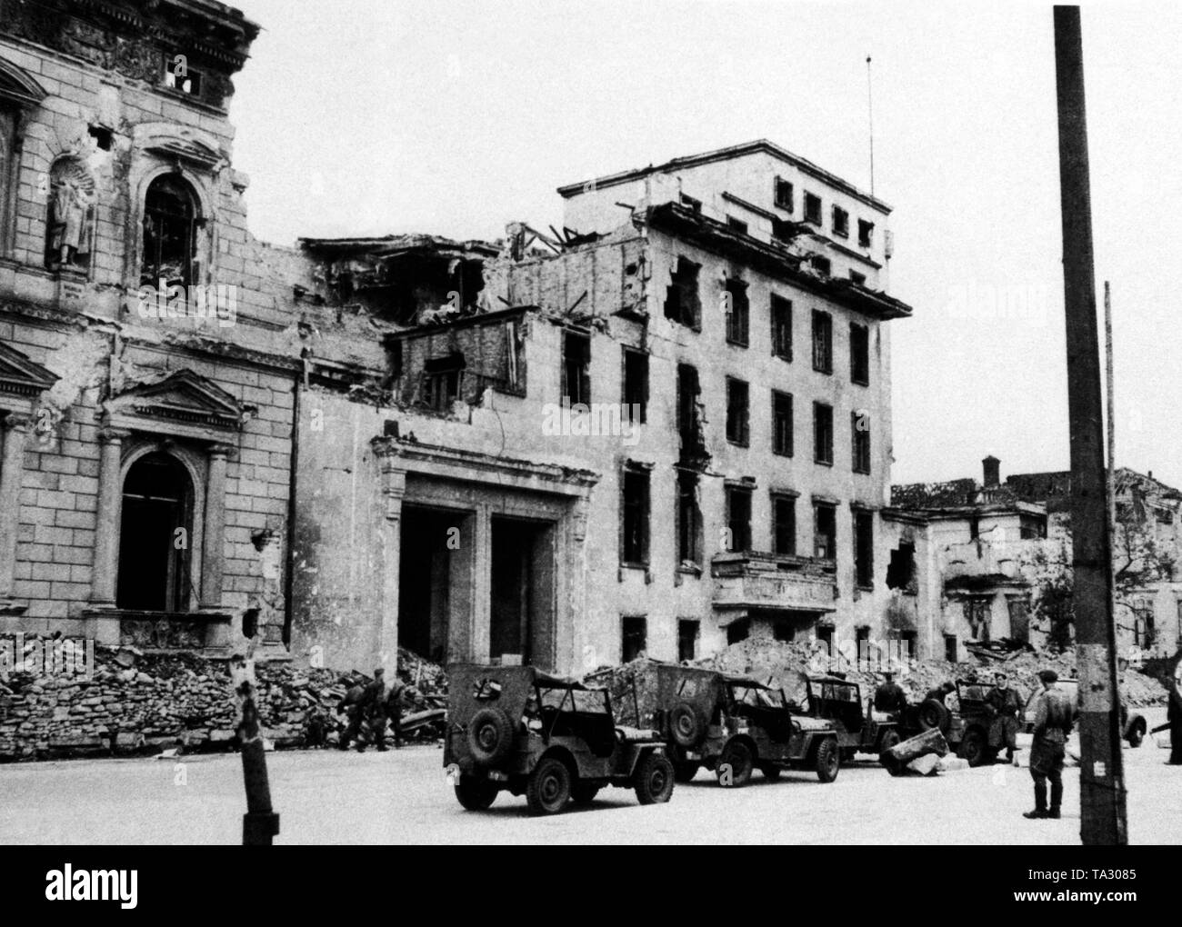 American jeeps park in front of the portal of the destroyed Reich Chancellery in Wilhelmstrasse. On the left, a part of the old Radziwill Palais, originally the official residence of the Chancellor. In the center, the extension from the Weimar Republic (1929/30), which Albert Speer had burst in 1938, in order to gain access to the main courtyard of the New Reich Chancellery. Stock Photo