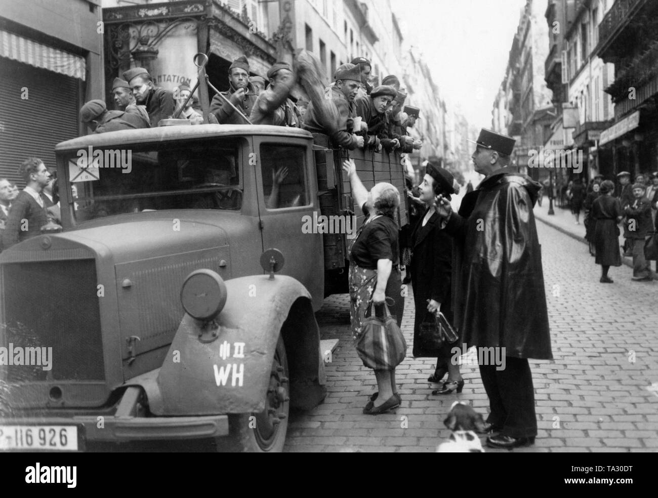 A truck with French soldiers in the Rue des Martyrs in Paris. The soldiers are driven in a German lorry through Paris, which stops here, so that Parisians can supply their compatriots. Stock Photo