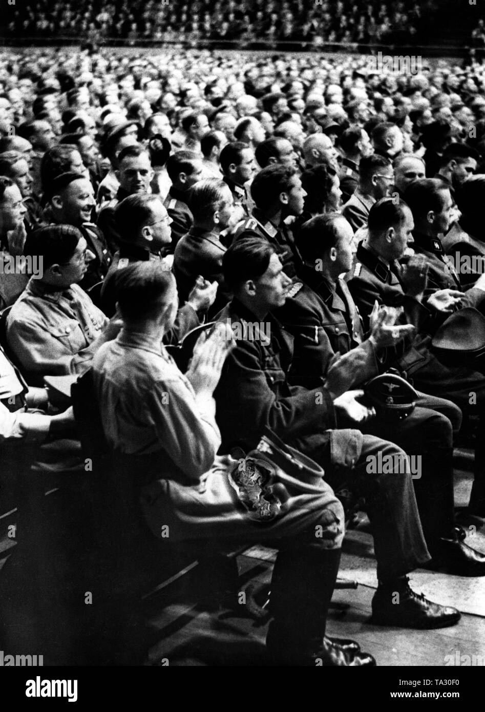 Members of the Wehrmacht and party members applaud after the ministers' speech. Stock Photo