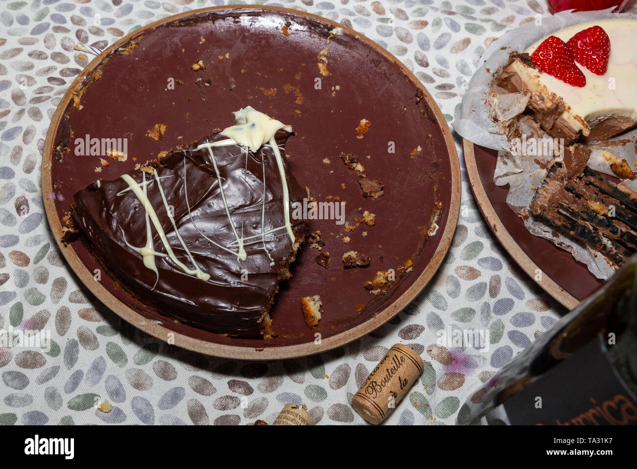 Remaining slice of chocolate cake and of strawberry and white chocolate cake on a table, sweet dessert on a birthday party. Stock Photo