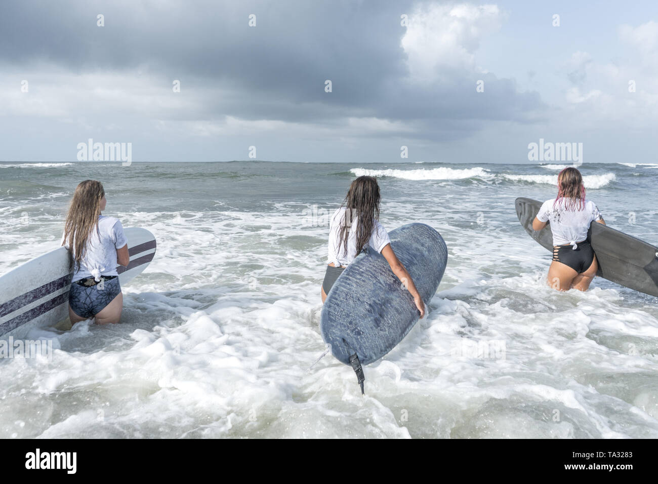 Three surfer women in white t-shirt go to the ocean with boards Stock Photo  - Alamy