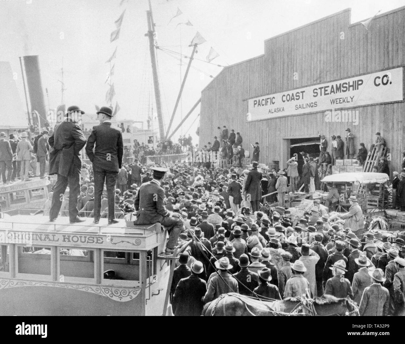 Gold seekers are gathering at the quay of the Pacific Coast Steamship Company in San Francisco to get a place on one of the ships heading to Alaska. Stock Photo