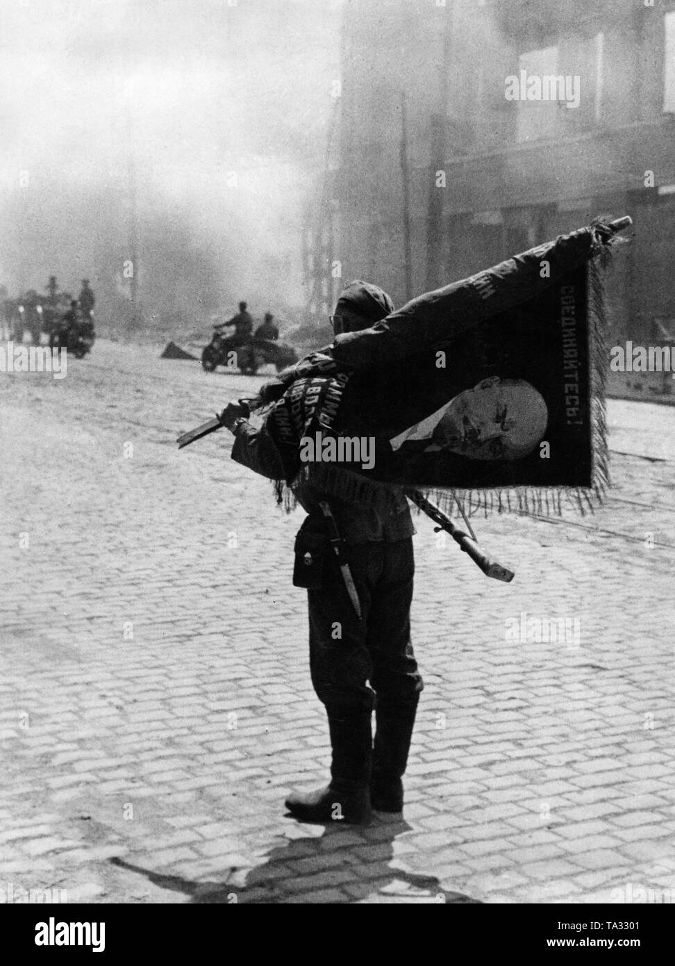 A soldier of the Wehrmacht with a captured Lenin flag after the conquest of Brest Litovsk. Stock Photo