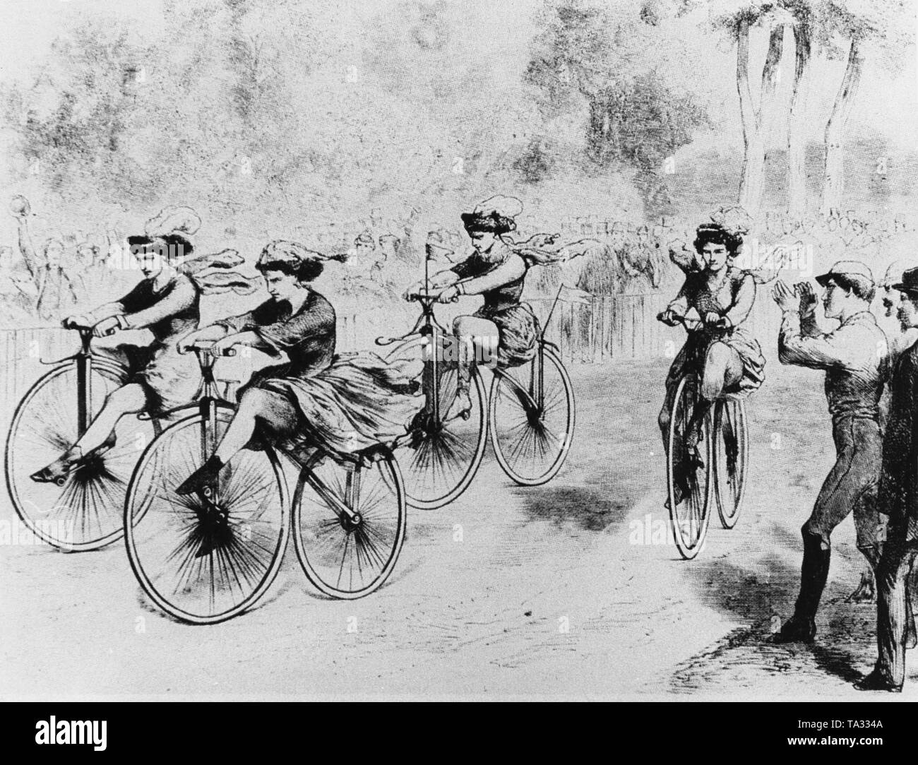 Photo of a women's cycling race in Paris. On display, four young women riding down a street. On the left and right side of the road are spectators. Stock Photo