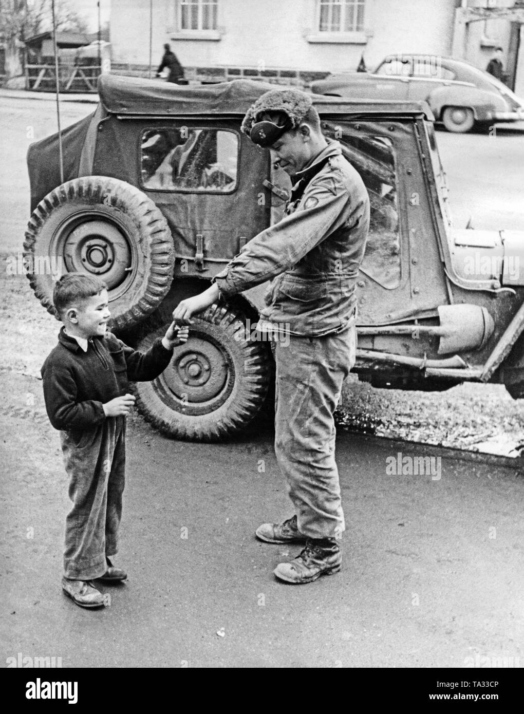 An American soldier gives a boy chewing gum. After the end of the war, many US soldiers were surprised that they did not experience any opposition from the German population. Stock Photo