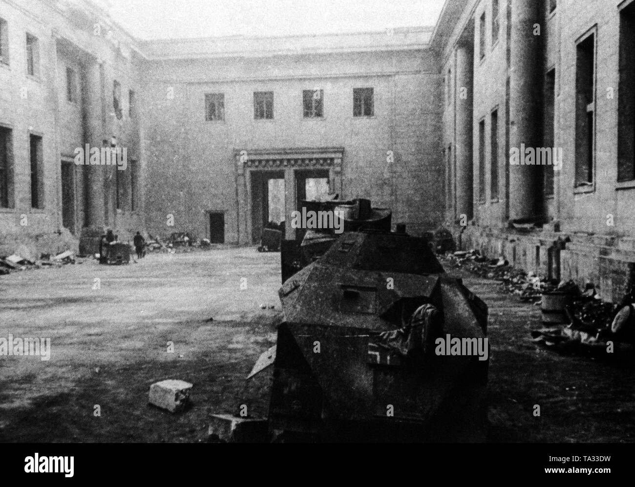 Photo of the main courtyard of the destroyed Reich Chancellery immediately after its capture by the Soviet troops. In the foreground, the wreck of a shot down German armored car, in the background the large portal to Wilhelmstrasse. Stock Photo