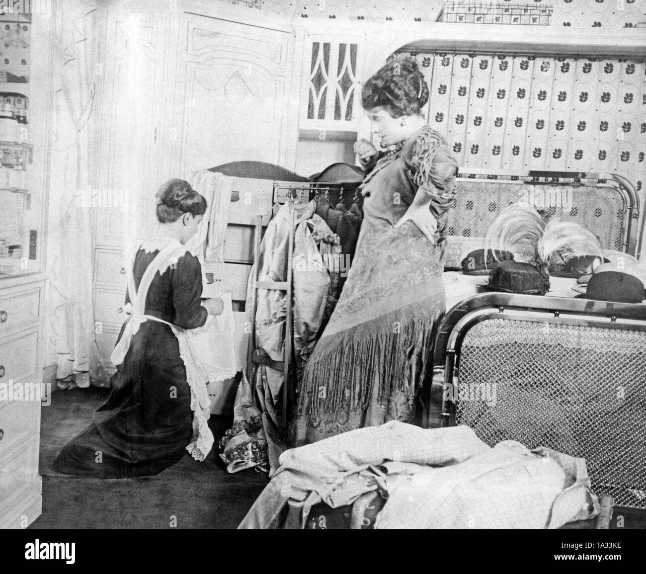 A maid packs the suitcase of a lady during a journey. Undated photo from around 1910. Stock Photo
