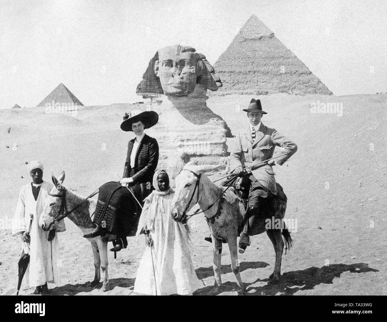 The German Crown Prince William, the eldest son of Emperor William II, and his wife Cecilia pose on donkeys in front of the Sphinx in Giza, in the background the pyramids. A trip to Egypt was considered an expensive and extravagant adventure at that time. Stock Photo
