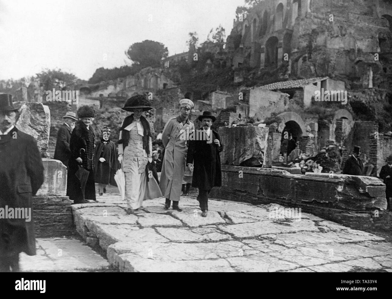 During their stay in Rome, the German Crown Princess Cecilie von Mecklenburg (front left), together with her husband Crown Prince Wilhelm of Prussia (front left) visited the Forum Romanum under the guidance of Prof. Boni (front right). Left behind the Crown Princess is the Italian King Victor Emanuel III in uniform. Stock Photo