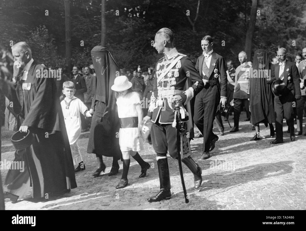 On July 6, Prince Sigismund was killed in a riding accident in Lucerne. A few days later he was buried near Berlin in Nikolskoe. In the funeral procession the clergy is followed by the members of the House of Prussia. 1st row from left to right: Prince Friedrich Karl, the widow Princess Marie Louise (b. Princess zu Schaumburg-Lippe), Princess Louise, Crown Prince Wilhelm. 2nd row: Prince Friedrich Leopold of Prussia. 3rd row: Crown Princess Cecilie. 4th row from left to right: Prince Oskar and Prince August Wilhelm. Stock Photo