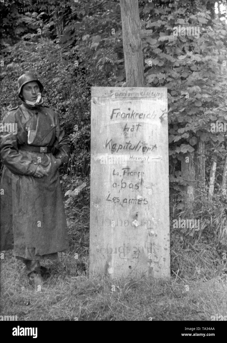 A rider in his dust coat is posing next to a sign announcing the capitulation of the French troops. Stock Photo