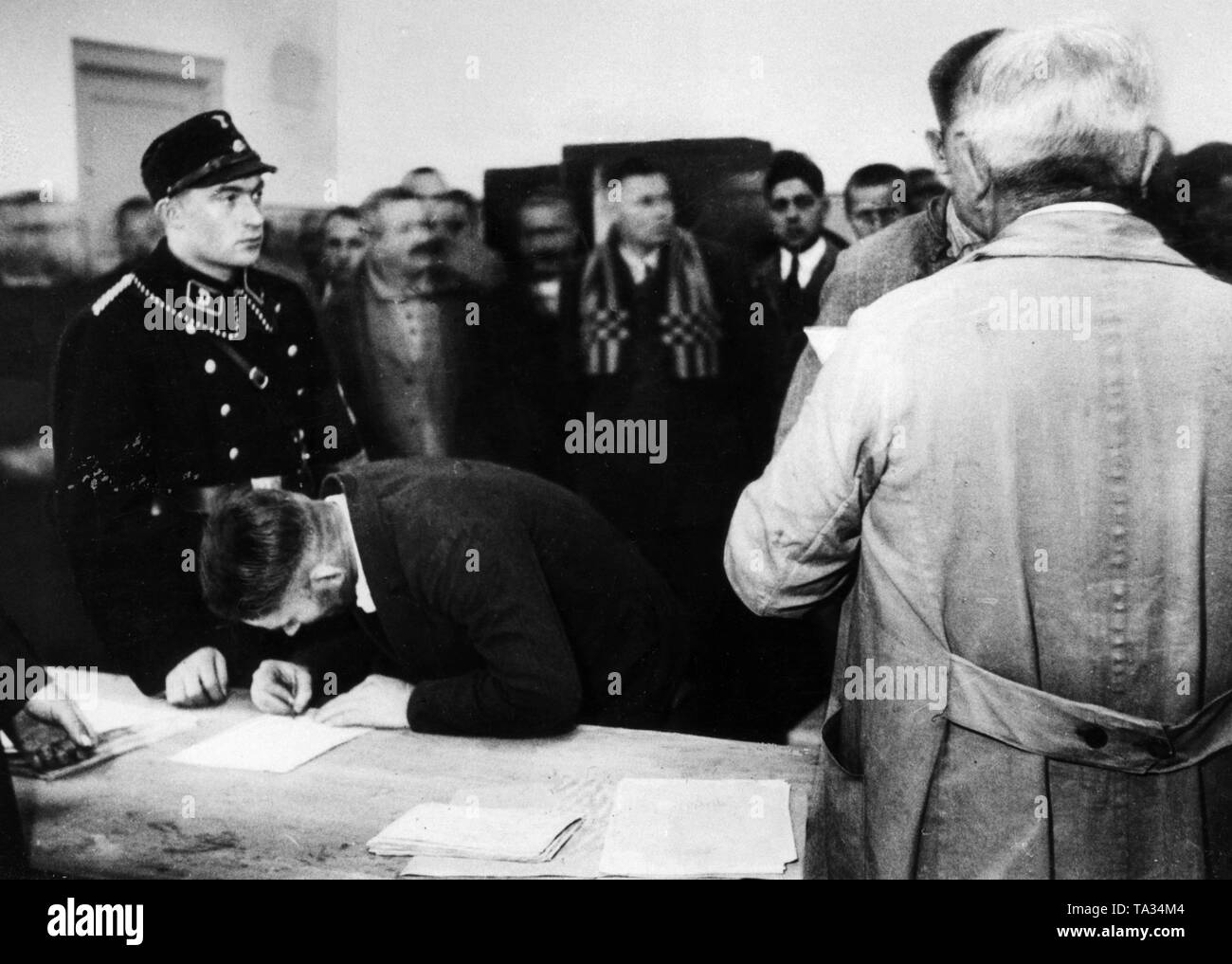 After the Reichstag election victory in November 1933, the Nazi government ordered the release of of about 6,000 political prisoners from the concentration camps as part of a 'Gnadenaktion' (act of mercy) at Christmas. Here, the amnestied men sign their discharge papers in the presence of the guards Dachau Concentration Camp. Stock Photo