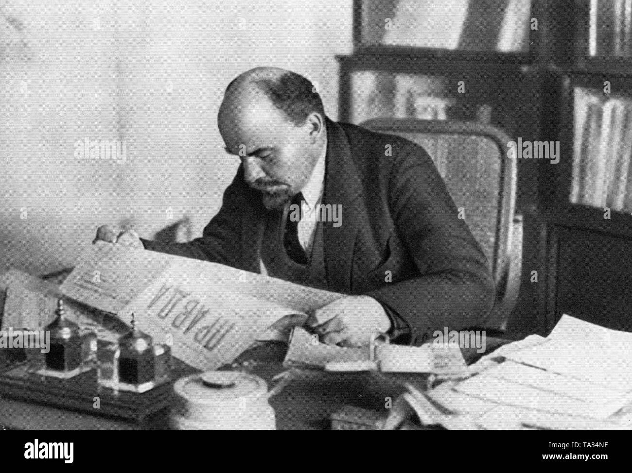 Vladimir Lenin reads in his office at the desk the newspaper Pravda on October 16. 1918 Stock Photo