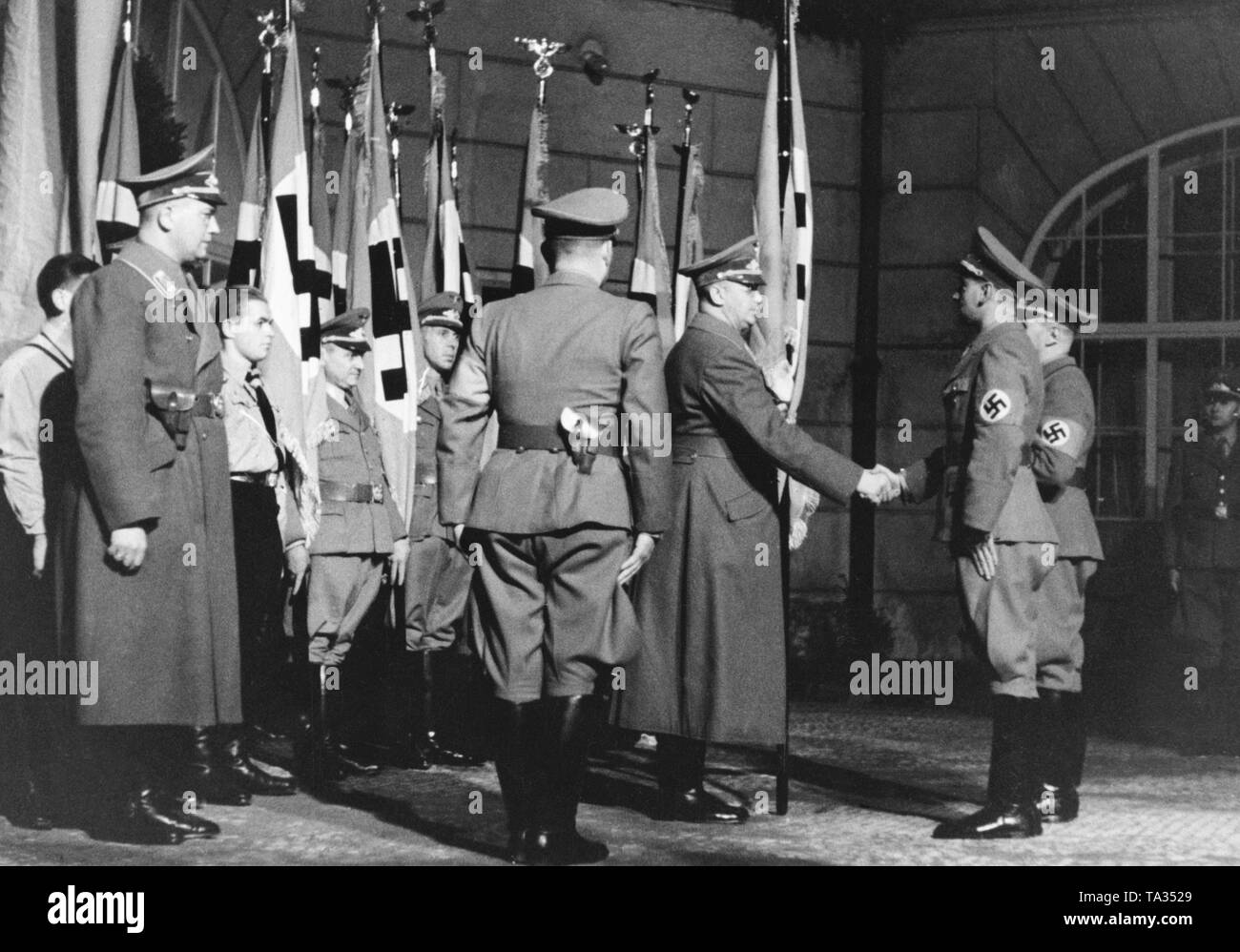 On the occasion of Robert Ley's visit in Prague, the Gauleiter of the Sudetenland Konrad Henlein hands over flags to 32 local groups. Since March 1939, the areas of Bohemia and Moravia had been under German occupation. Stock Photo