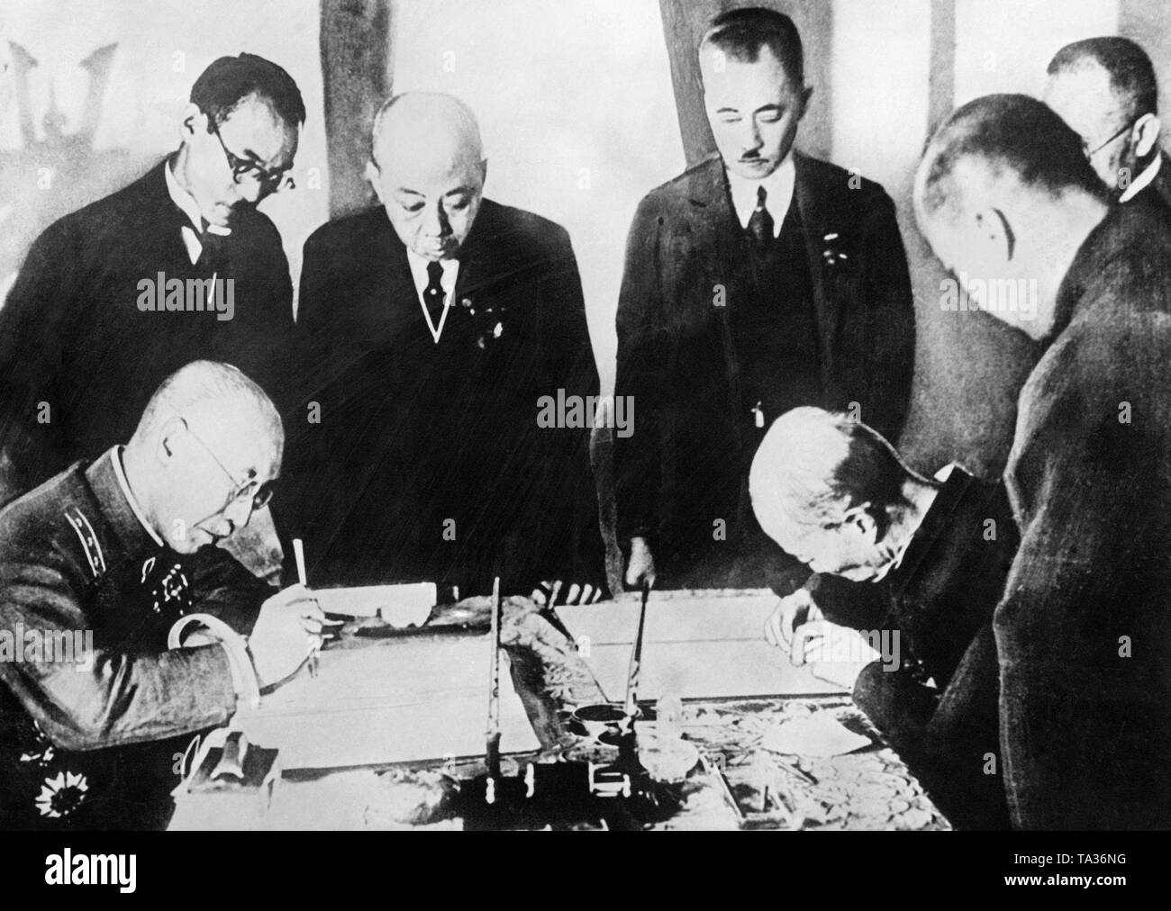 Representatives of the newly founded Manchukuo state and Japan sign a friendship treaty on October 6, 1932 in the capital of Manchukuo, Changchun. General Nobuyoshi Muto (left, sitting) represents Japan. Prime Minister Zheng Xiaoxu standing in the middle) and Foreign Minister Xie Jieshi (Hsi Tschei Shi) (right, sitting) are present as representatives of Manchukuo. Stock Photo